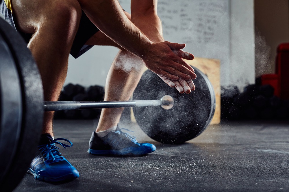 Seorang pria sedang melakukan latihan angkat beban di gym