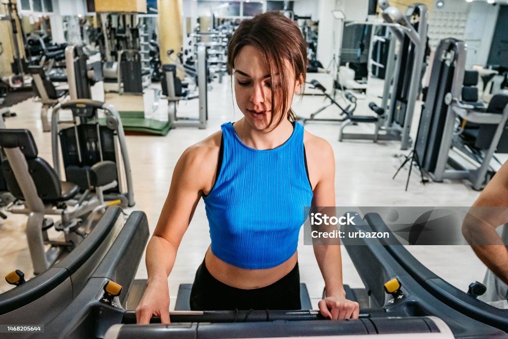 Seorang wanita sedang berlari di atas treadmill di gym