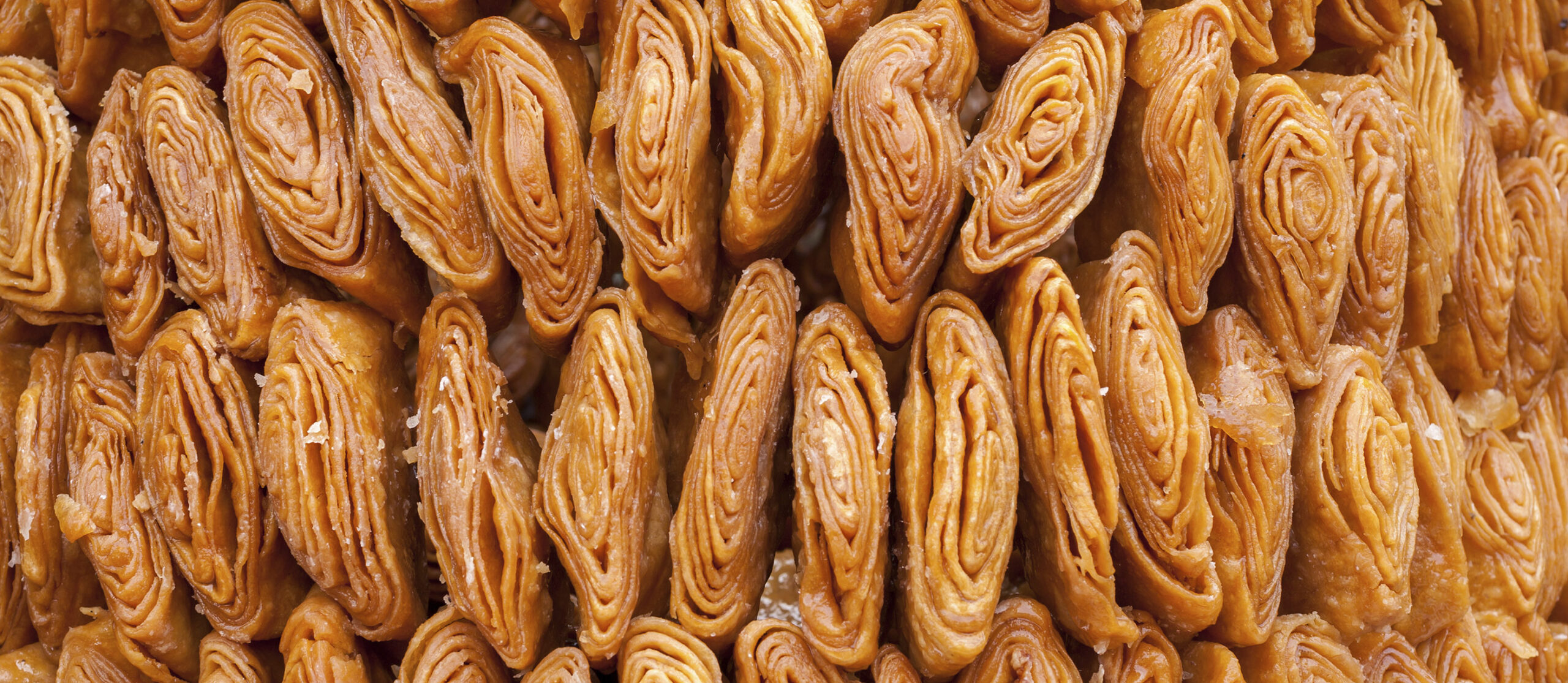 Close-up of Khaja being prepared, showcasing the intricate layers of dough and ghee, symbolizing the craftsmanship and care put into its creation.