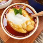 Semangkuk Bubur Sumsum yang lembut dan manis, disiram dengan sirup gula merah dan dihiasi daun pandan segar