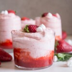 Strawberry mousse yang lembut dan menggoda selera, disajikan dalam gelas elegan dengan hiasan strawberry segar dan daun mint