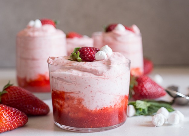 Strawberry mousse yang lembut dan menggoda selera, disajikan dalam gelas elegan dengan hiasan strawberry segar dan daun mint