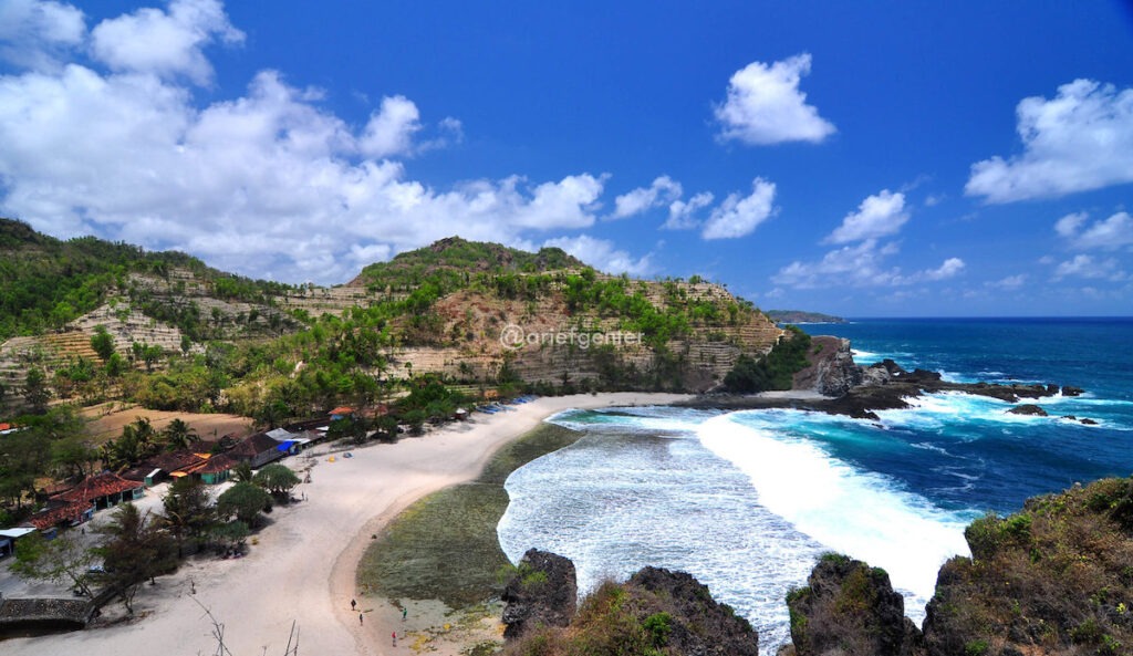 Pemandangan indah Pantai Siung dengan pasir putih bersih dan tebing karang yang menjulang tinggi, menciptakan suasana eksotis yang memukau