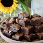 Fudgy Brownies Lezat: Potongan fudgy brownies yang tebal dan lembut, dengan permukaan yang retak sempurna, siap disantap