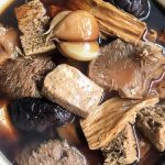 Semangkuk Bak Kut Teh dengan kuah rempah aromatik, potongan iga babi empuk, dan tahu kulit