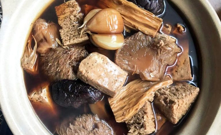 Semangkuk Bak Kut Teh dengan kuah rempah aromatik, potongan iga babi empuk, dan tahu kulit