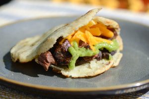 A plate of assorted arepas with different fillings, including avocado and pork.